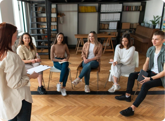 Groepscoaching in een moderne trainingsruimte met een begeleider en deelnemers in gesprek